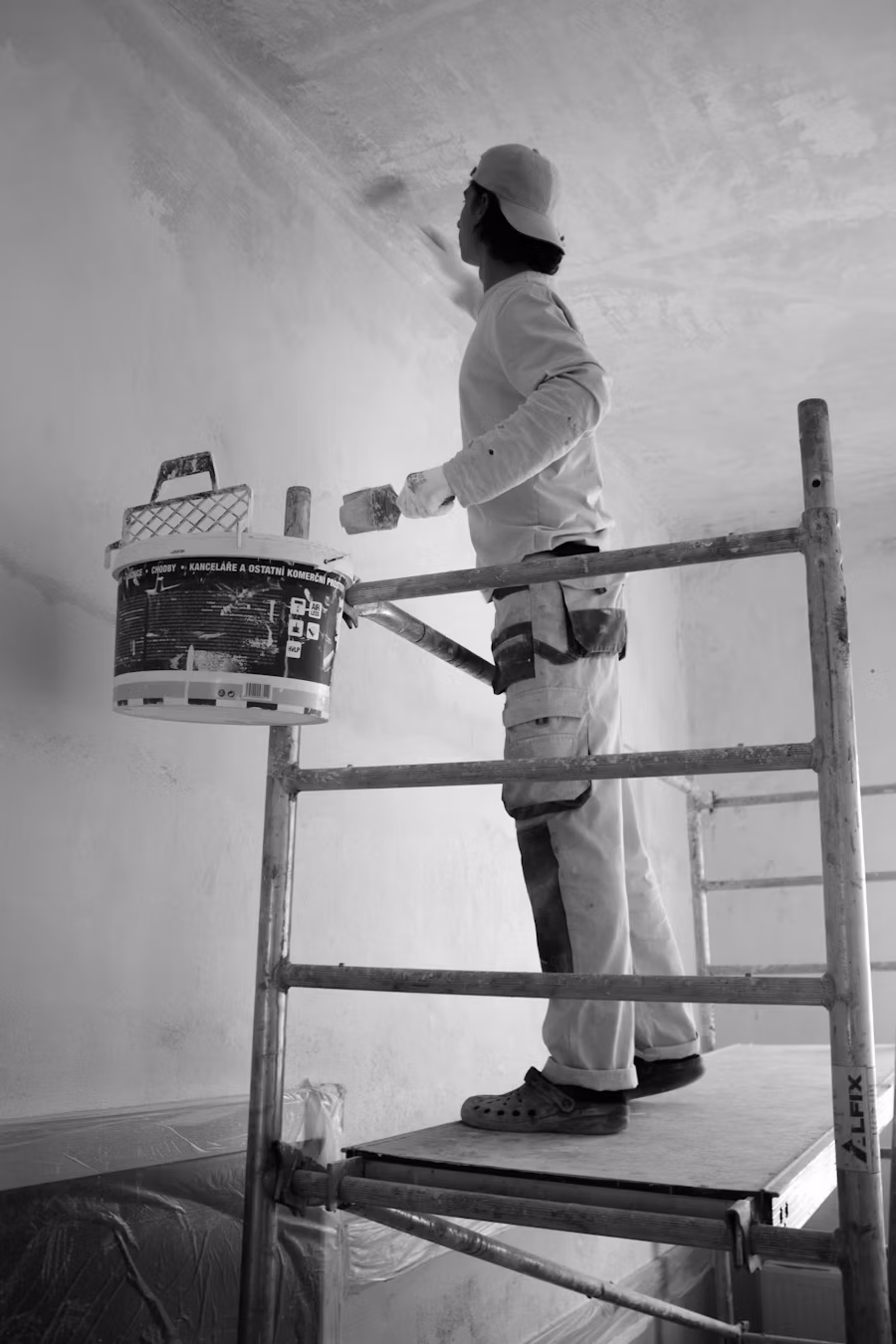 Professional painter on scaffolding painting a ceiling inside a home